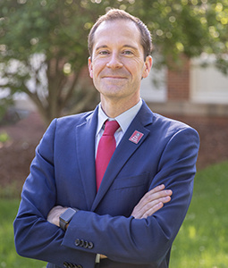 Headshot of Bradley Cole outdoors. He is wearing a suit and tie.