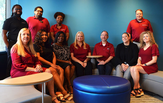 A group of advisors both black and white pose for a picture on a set of couches. 