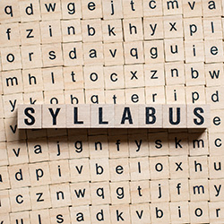 Wooden letter tiles spelling “SYLLABUS” against a background of alphabet tiles.