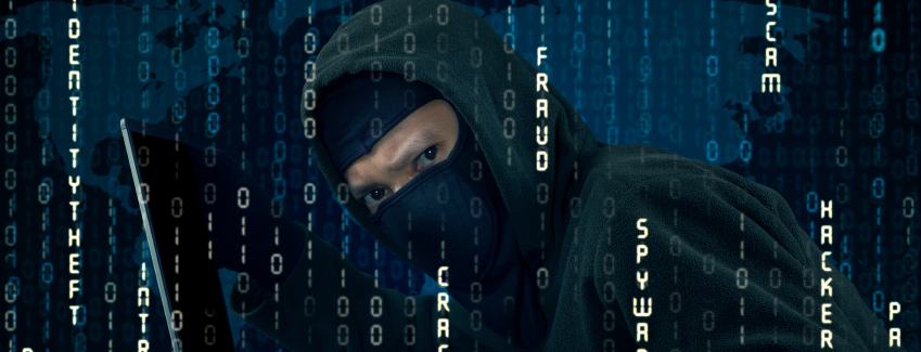 A person wearing a ski mask looks suspicious in front of words such as fraud, hacker, and spyware.