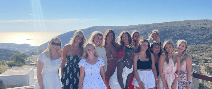 Students study abroad taking a group photo with a scenic view in the background