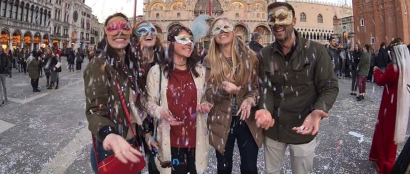 Group of students wearing masks throw confetti in the air