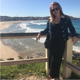 Woman standing in front of a beach in the sun