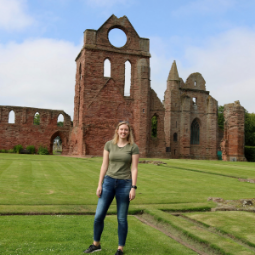 Students stands in front of old building ruins