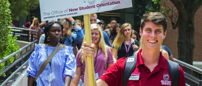 Orientation leader holding college sign