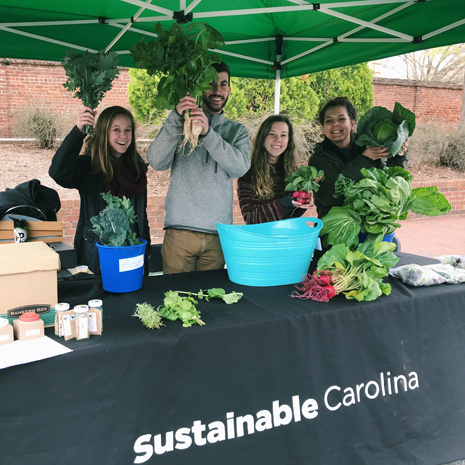 students holding up produce at the farmers market