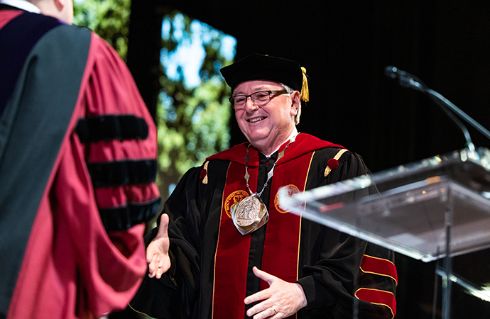 President Amiridis shaking hands at the podium.