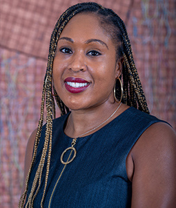 woman with braided hair smiling with a dark navy dress on 