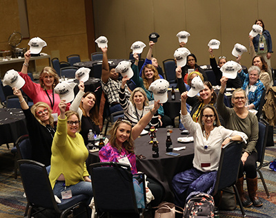 alumni holding up hats