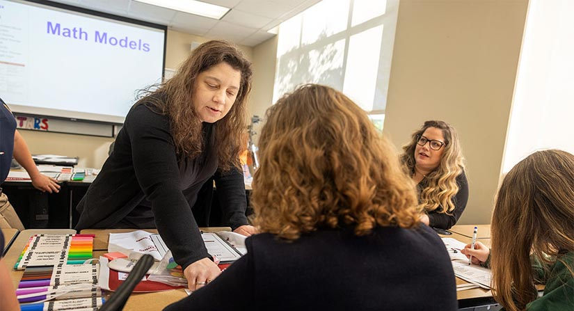 teacher leans in to point at student work.