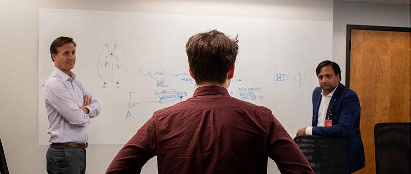 Kevin Gagnon talks to his two mentors in a classroom.