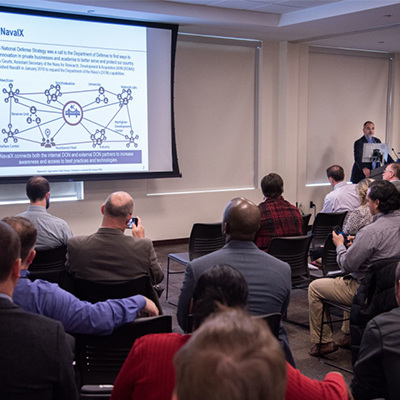 people sit watching a presentation at the kickoff meeting