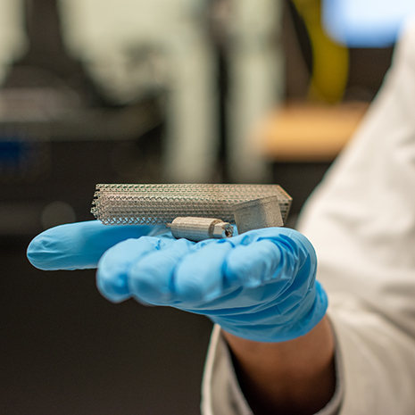 composite metal pieces rest on a gloved hand