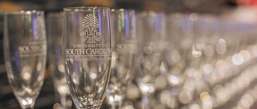 Close up of champagne glasses with 'South Carolina Honors College' etched onto them.