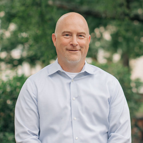 Smiling man in light blue, long sleeve collared shirt