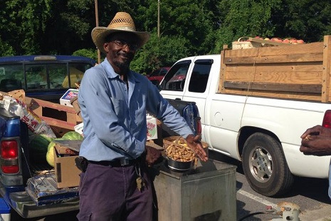 Farmer standing in front of a truck with a pot full of vegetables