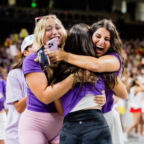 Three women hug excitedly during 2025 sorority bid day at USC