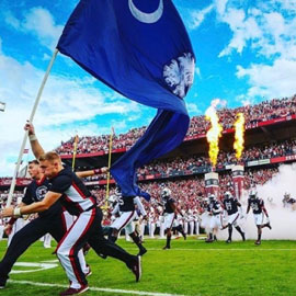 Cheerleaders running with uofsc flag at Williams Brice stadium