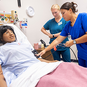 Two medical students train on a human patient simulator.