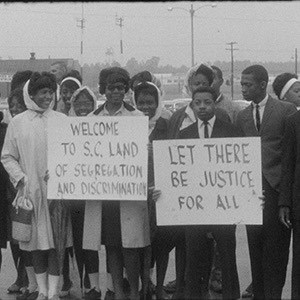 Civil rights protesters stand with signs reading "Let there be justice for all"