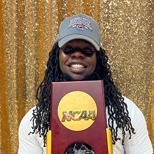 Jonathan Hampton holding the Women's Basketball NCAA Championship trophy.