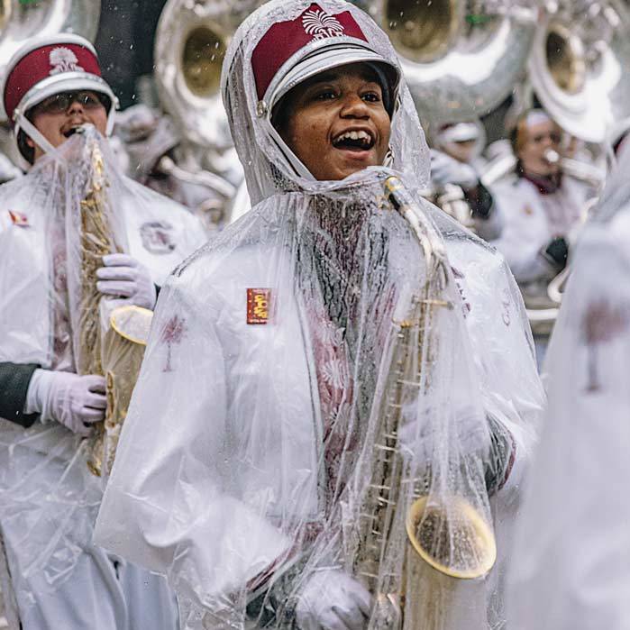 Saxophonist Jeniya Brown smiles through the rain as the band marches down 34th street.